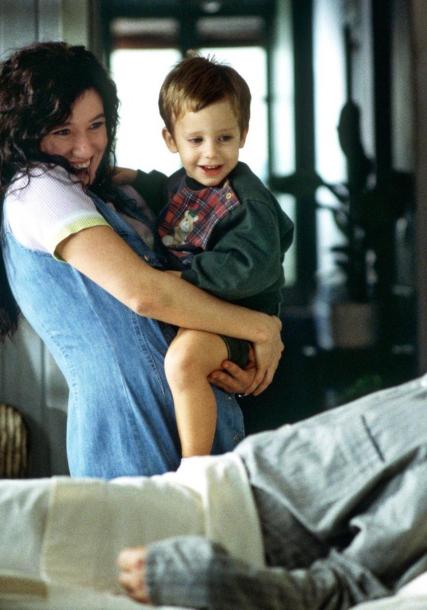 Lola Dueñas with a child in her arms and Javier Bardem in bed.